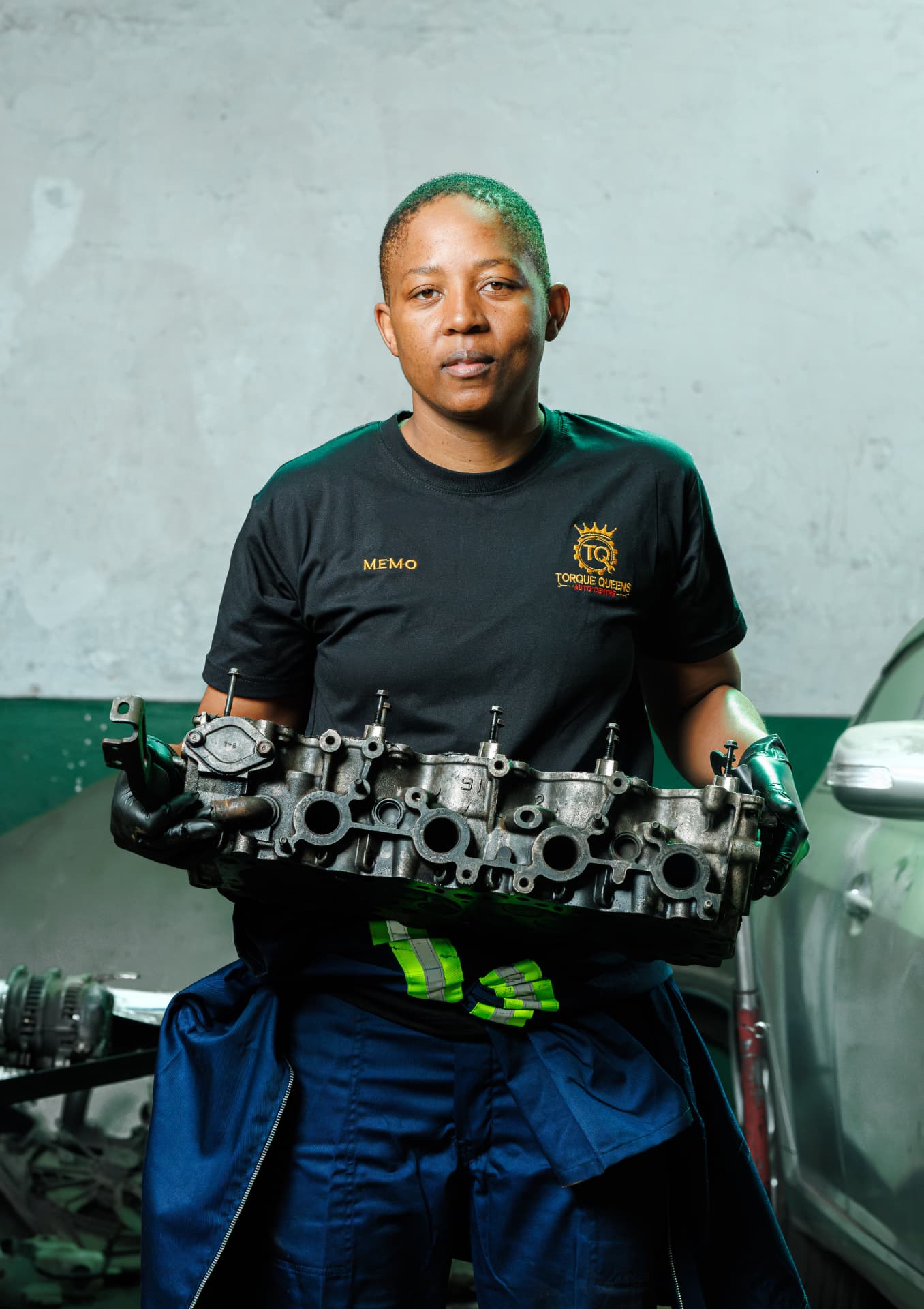 Memo holding a cylinder head in the Torque Queens workshop