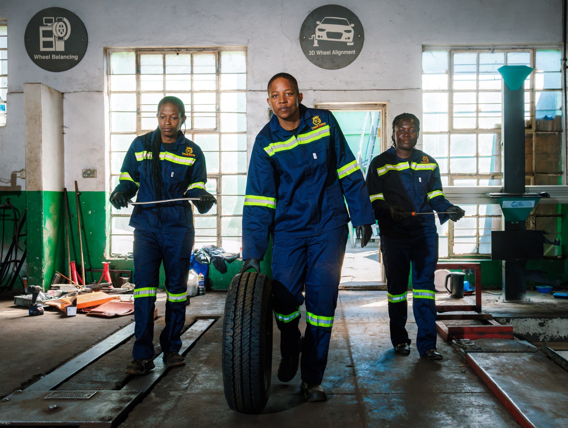 The Torque Queens team walking through the workshop with a tyre and tools